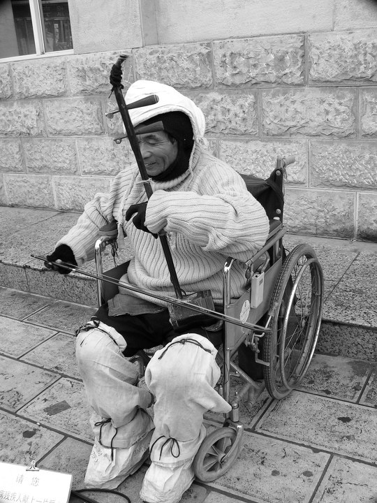 停车时听到一阵悠扬的胡琴声,循声转过街角,见一轮椅老人正在拉琴