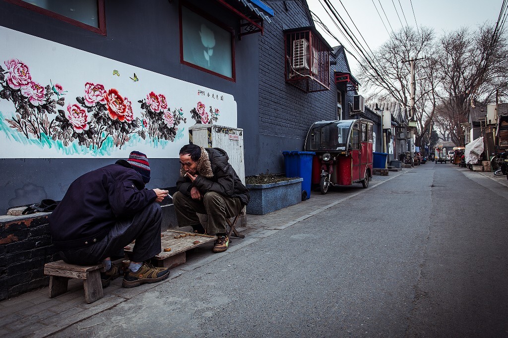 老北京们在自家的胡同跟前抽着烟,下着棋,泰然自若