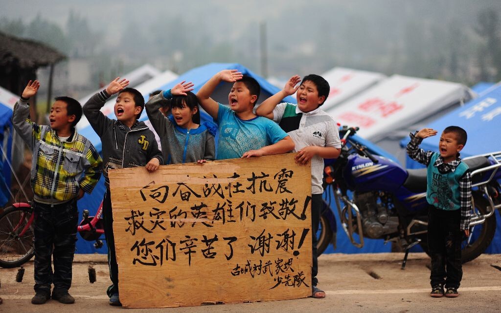 0级强烈地震抗震救灾进入过渡安置阶段,震区的孩子们站在路边,向来往